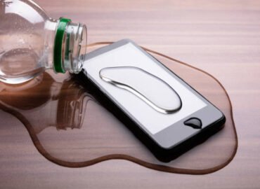 Close-up Of Spilled Water On Smart Phone Over Wooden Desk Danysonic telecoms