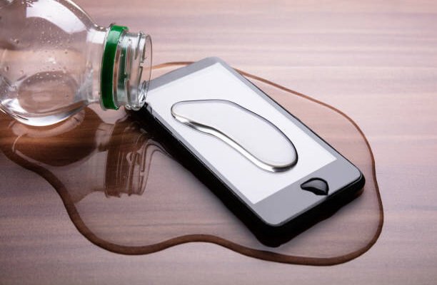 Close-up Of Spilled Water On Smart Phone Over Wooden Desk Danysonic telecoms